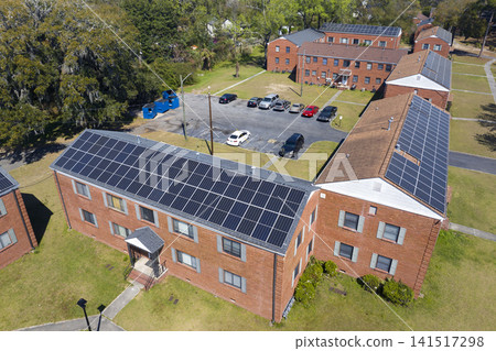 Suburban apartment buildings equipped with solar rooftops, producing green electricity and illustrating sustainable development and environmentally conscious housing solutions. Suburban apartment buildings equipped with solar rooftops, producing green electricity and illustrating sustainable development and environmentally conscious housing solutions. 141517298