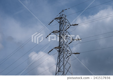 Power transmission towers and high-voltage lines against a cloudy blue sky. Power transmission towers and high-voltage lines against a cloudy blue sky. 141517656