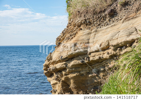 海岸邊裸露的含礫石岩層和蔚藍的大海 海岸邊裸露的含礫石岩層和蔚藍的大海 141518717