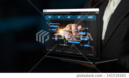 A professional businesswoman uses a laptop to interact with innovative project management software, displaying a dynamic Gantt chart in a modern office setting. Sigmoid A professional businesswoman uses a laptop to interact with innovative project management software, displaying a dynamic Gantt chart in a modern office setting. Sigmoid 141519163