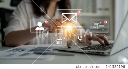 Person Using Laptop with Light Bulb Icon Illustrating Ideas and Notification Alerts from Email and Messaging Applications. Sentient Person Using Laptop with Light Bulb Icon Illustrating Ideas and Notification Alerts from Email and Messaging Applications. Sentient 141520196