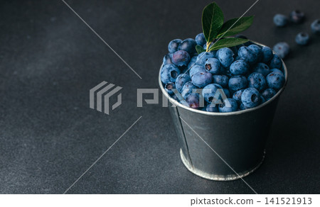 Fresh Blueberries with Green Leaves in Metal Bucket on Dark Background 141521913