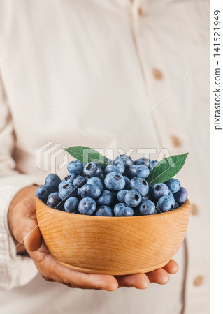 Hand Holding Wooden Bowl with Fresh Blueberries Vertical Healthy Food Concept Hand Holding Wooden Bowl with Fresh Blueberries Vertical Healthy Food Concept 141521949