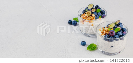 Blueberry chia pudding with granola and fresh berries in glass cups Blueberry chia pudding with granola and fresh berries in glass cups 141522015