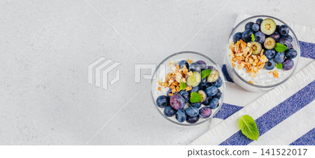 Blueberry yogurt parfait with granola in glass cups top view Blueberry yogurt parfait with granola in glass cups top view 141522017