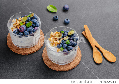 Blueberry chia yogurt parfait with granola on dark background Blueberry chia yogurt parfait with granola on dark background 141522043