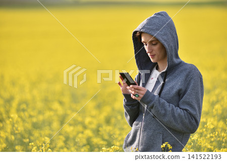 Woman in a gray hoodie using her phone outdoors Woman in a gray hoodie using her phone outdoors 141522193
