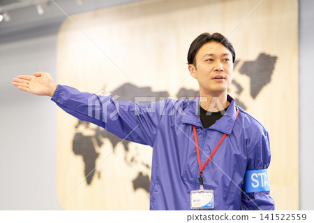 A male staff member guiding visitors at the event venue. A male staff member guiding visitors at the event venue. 141522559