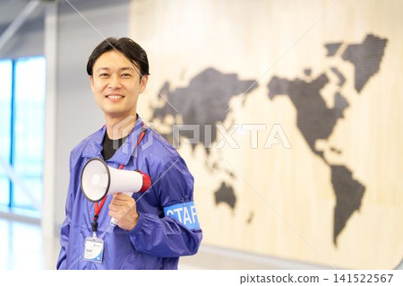 A male event staff member stands with a megaphone and a smile on his face. A male event staff member stands with a megaphone and a smile on his face. 141522567