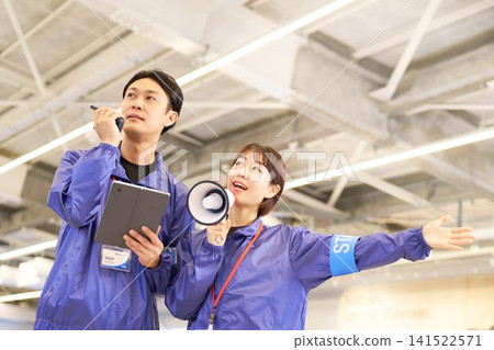 一名女工作人員使用揚聲器發出指示,而一名男工作人員則使用對講機與她溝通。 一名女工作人員使用揚聲器發出指示,而一名男工作人員則使用對講機與她溝通。 141522571