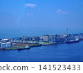 Aerial view of the coastal industrial area and large ships anchored in the harbor, under a clear blue sky. 141523433