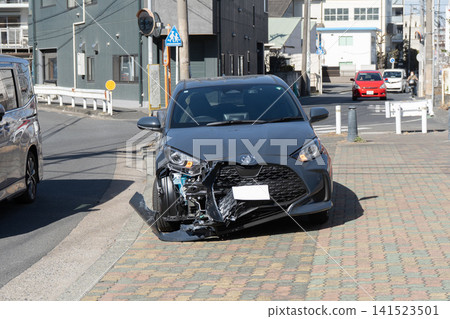 A passenger car with a damaged right front bumper from a traffic accident, and a passing car. A passenger car with a damaged right front bumper from a traffic accident, and a passing car. 141523501