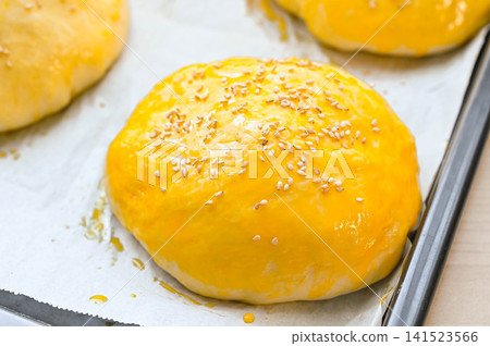Bread filled with ingredients, brushed with egg, topped with sesame seeds, before baking. Bread filled with ingredients, brushed with egg, topped with sesame seeds, before baking. 141523566