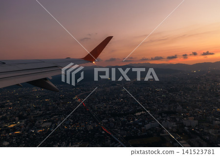 The airport at dusk, and the beautiful sunset sky and cityscape viewed from the airplane window. The airport at dusk, and the beautiful sunset sky and cityscape viewed from the airplane window. 141523781