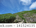 Stairs on a mountain path leading to the blue sky and a green ridgeline 141524135