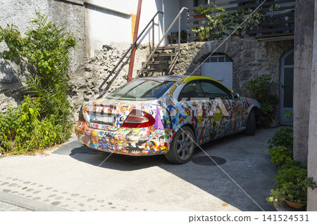 A car is covered in a colorful, intricate decal wrap featuring numerous cartoon characters. A car is covered in a colorful, intricate decal wrap featuring numerous cartoon characters. 141524531