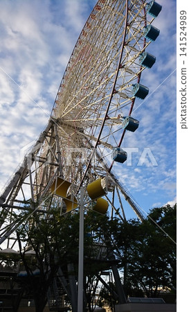 The Ferris wheel next to the Osaka Aquarium Kaiyukan spins against the backdrop of a blue sky. The Ferris wheel next to the Osaka Aquarium Kaiyukan spins against the backdrop of a blue sky. 141524989