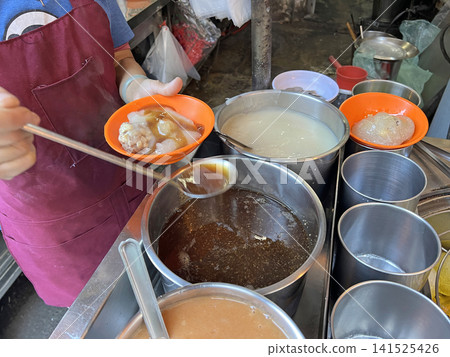 在傳統早餐店裡拍攝店員在肉圓上淋上醬汁 141525426