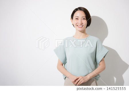 A Japanese woman's upper body is shown against a white background, wearing a short-sleeved shirt and smiling. The image conveys a bright and approachable image of a working woman, and she is looking directly at the camera. A Japanese woman's upper body is shown against a white background, wearing a short-sleeved shirt and smiling. The image conveys a bright and approachable image of a working woman, and she is looking directly at the camera. 141525555