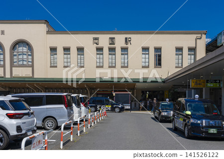 A view of the JR Ryogoku Station West Exit building and rotary under a clear blue sky. 141526122