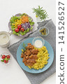 A lunch set featuring butter chicken curry and colorful vegetables served on a blue plate. 141526527
