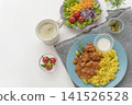 A lunch set featuring butter chicken curry and colorful vegetables served on a blue plate. 141526528
