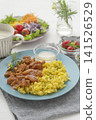 A lunch set featuring butter chicken curry and colorful vegetables served on a blue plate. 141526529