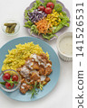 A lunch set featuring butter chicken curry and colorful vegetables served on a blue plate. 141526531