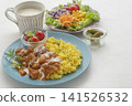 A lunch set featuring butter chicken curry and colorful vegetables served on a blue plate. 141526532