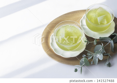 冰涼綠茶擺放在木托盤上；夏日午後，陽光透過樹葉灑下斑駁的光影。 141527488