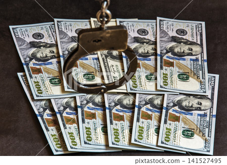 Handcuffs on one hundred banknotes of US dollars Handcuffs on one hundred banknotes of US dollars 141527495