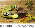 Glass cup of tea, jam and lemon on a background of a wooden surface and yellow leaves 141527498