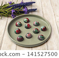 Collectible handmade tempered chocolate sweets with a glossy painted body on a round plate 141527500