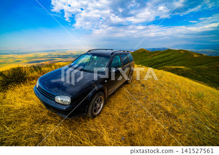 Black Station Wagon on Hilltop Overlooking Valley Black Station Wagon on Hilltop Overlooking Valley 141527561