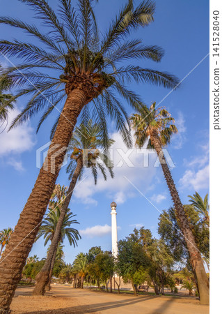 Historic Monument to the Discoverers at La Rabida Friary in Huelva, Andalusia, Spain. Sunny landmark surrounded by palm trees under a cloudy blue sky. Historic Monument to the Discoverers at La Rabida Friary in Huelva, Andalusia, Spain. Sunny landmark surrounded by palm trees under a cloudy blue sky. 141528040
