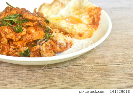 spicy stir fried slice pork meat with chili and basil leaf curry topping egg and rice on plate   141529018