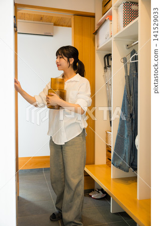 A woman putting away her belongings in the mudroom storage area. A woman putting away her belongings in the mudroom storage area. 141529033