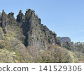 A rocky mountain towering on top of a mountain 141529306