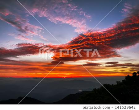 A dramatic sunrise and dawn viewed from the summit of Mt. Nyohō in Nikko, with a gradient of crimson hues painting the mountain range. A dramatic sunrise and dawn viewed from the summit of Mt. Nyohō in Nikko, with a gradient of crimson hues painting the mountain range. 141529642