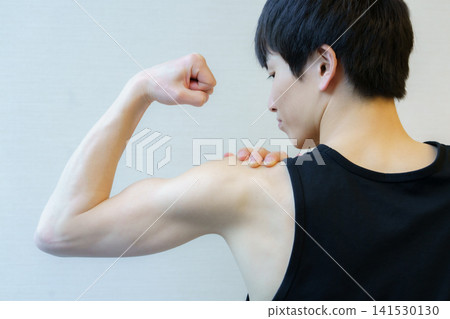 一位年輕日本男子的背影,他正在展示自己的手臂肌肉。 一位年輕日本男子的背影,他正在展示自己的手臂肌肉。 141530130