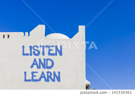Listen and learn words symbol. Concept words Listen and learn on beautiful white wall. Beautiful blue sky background. Business listen and learn support concept. Copy space. 141530361