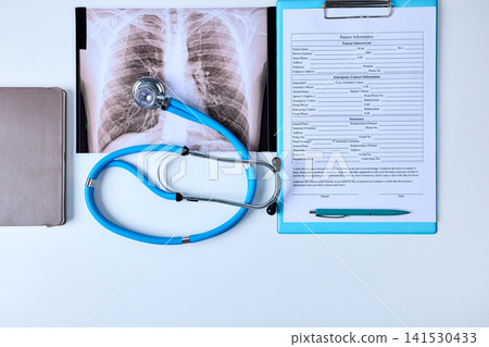 Stethoscope lies on a doctor's desk next to medical documents and a chest x-ray of a patient in a pulmonology department. Treatment of lung diseases Stethoscope lies on a doctor's desk next to medical documents and a chest x-ray of a patient in a pulmonology department. Treatment of lung diseases 141530433