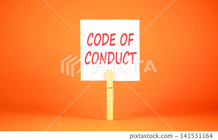 Code of conduct words symbol. Concept words Code of conduct on beautiful white paper on wooden clothespin. Beautiful orange background. Business Code of conduct concept. Copy space. Code of conduct words symbol. Concept words Code of conduct on beautiful white paper on wooden clothespin. Beautiful orange background. Business Code of conduct concept. Copy space. 141531164