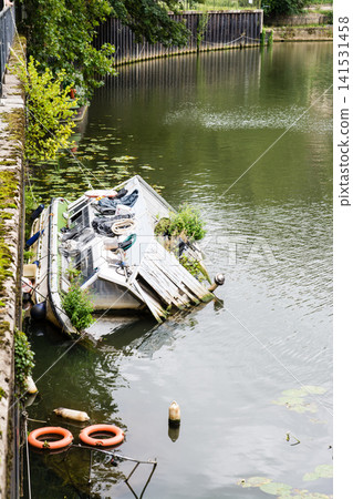 A destroyed and half-submerged canal boat on the river flowing through Bath, a UNESCO World Heritage site in the UK. A destroyed and half-submerged canal boat on the river flowing through Bath, a UNESCO World Heritage site in the UK. 141531458