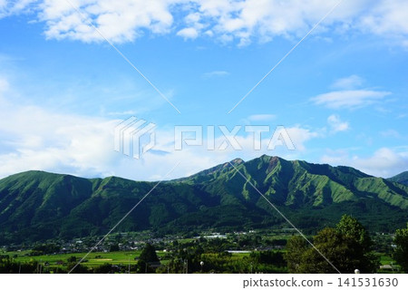 The summer scenery of the Aso mountain range, with its blue skies and white clouds, and lush green nature. The summer scenery of the Aso mountain range, with its blue skies and white clouds, and lush green nature. 141531630