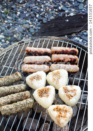 A barbecue in the bright sunshine: sausages and grilled rice balls placed on a round barbecue grill. A barbecue in the bright sunshine: sausages and grilled rice balls placed on a round barbecue grill. 141531657