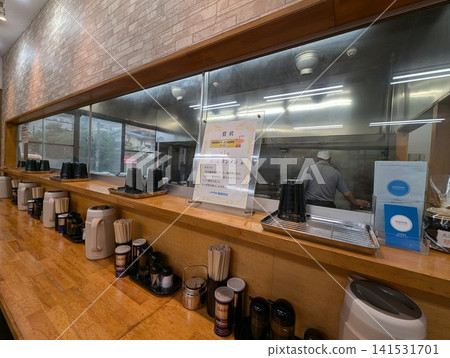 View of the ramen shop's kitchen and interior from the counter seats. View of the ramen shop's kitchen and interior from the counter seats. 141531701
