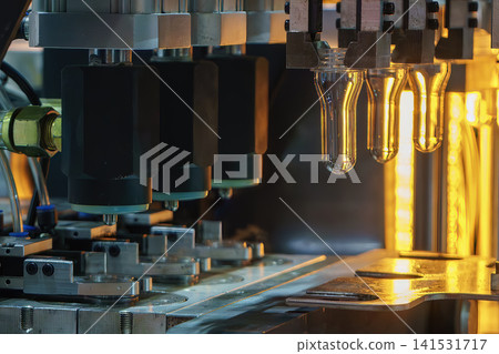 PET plastic preform shapes moving on a conveyor belt during the blowing process on a blow mold machine. PET plastic preform shapes moving on a conveyor belt during the blowing process on a blow mold machine. 141531717