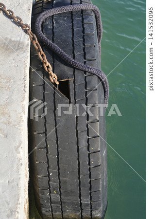 Damaged tire used as boat fender on a concrete dock Damaged tire used as boat fender on a concrete dock 141532096