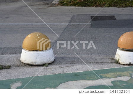 Concrete bollards on asphalt road edge Concrete bollards on asphalt road edge 141532104